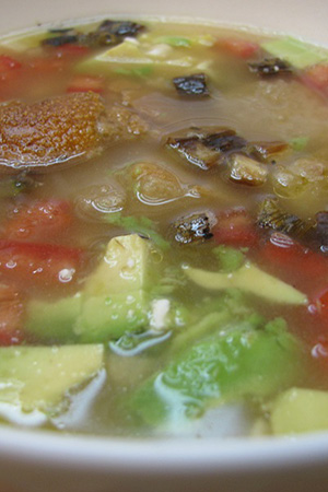 Mexican garlic soup with avocado, tomato and grilled green onions
