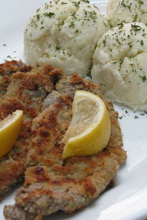 pan fried wiener schnitzel with lemon wedges and Hungarian mashed potatoes